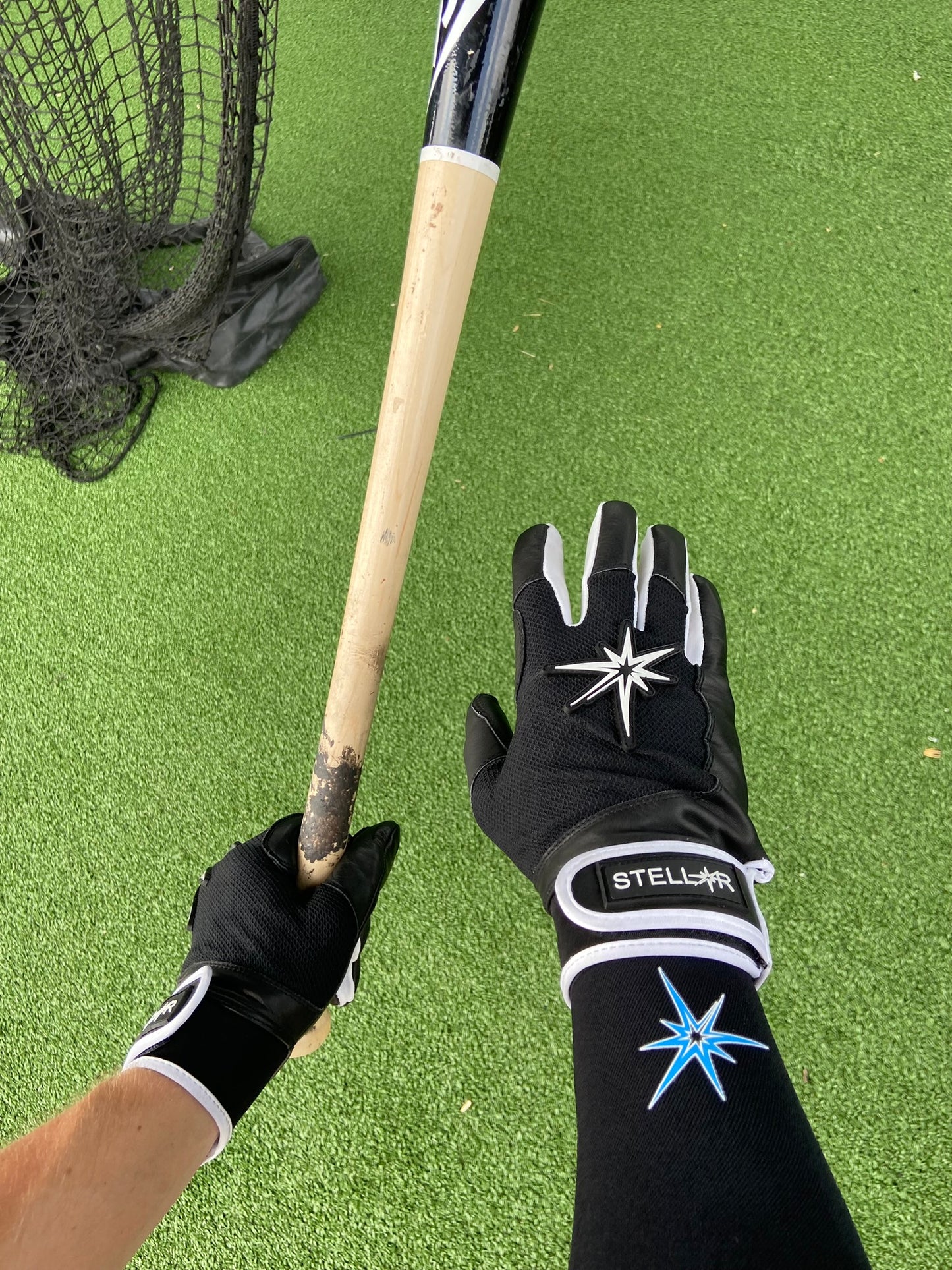 Black graduated compression arm sleeve with black batting gloves posing while holding a bat.
