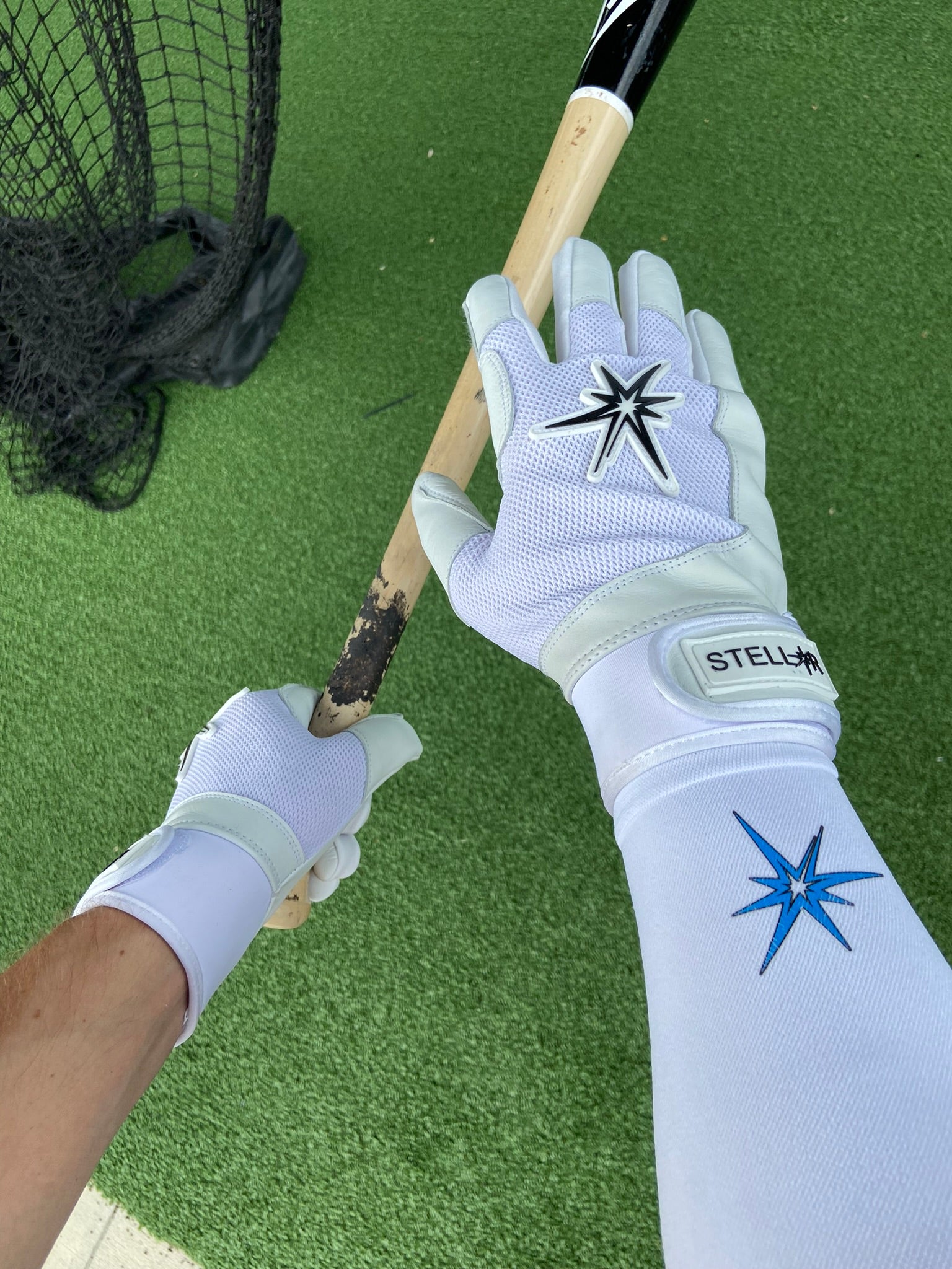 White graduated compression arm sleeve with white batting gloves posing while holding a bat.