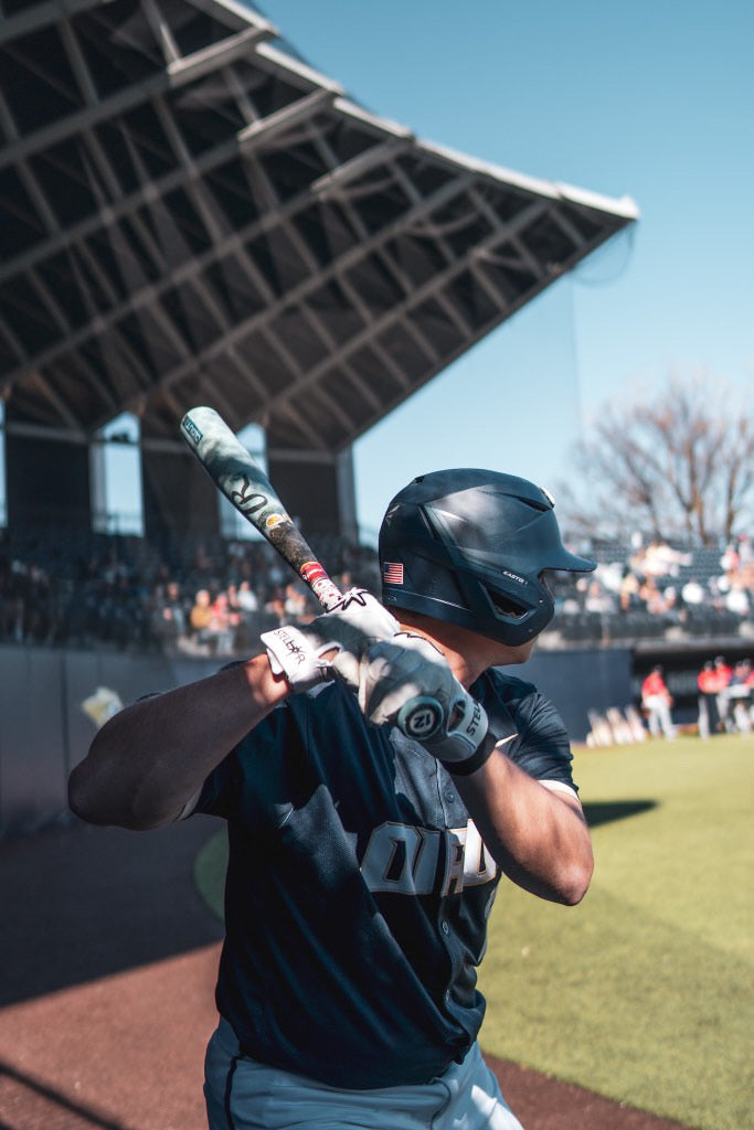 Baseball player holding a bat on a baseball field with a clear sky