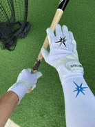 White graduated compression arm sleeve with white batting gloves posing while holding a bat.